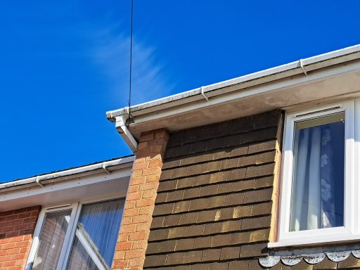 Corner of a house featuring brick and wooden cladding against a clear blue sky.
